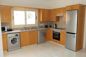 a kitchen with wooden cabinets and a stainless steel refrigerator at Anthorina Villa 7 in Protaras
