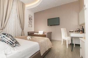 Pokój hotelowy z łóżkiem, biurkiem i telewizorem w obiekcie Elenoire Rooms & Suite w Rzymie