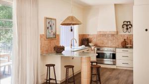 a kitchen with a counter and stools in it at Designed By Three Birds Renovation in Pearl Beach