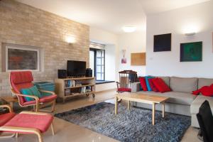 a living room with a couch and chairs and a tv at Carmel Home Mount Seaview in Haifa