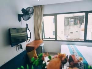 a bedroom with a bed and a tv and a window at okaeri hotel in Hanoi