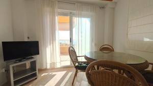 a living room with a table and a television at Parquemar III-IV Solo Familias!!! Serviplaya in Playa de Xeraco