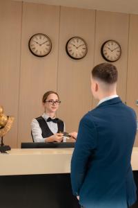 a man and a woman standing at a desk with clocks at Koral Boutique Hotel in Durrës