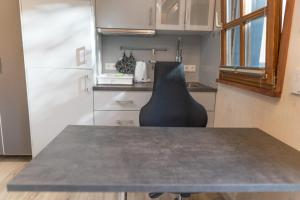 a kitchen with a table and a black chair in it at Il Giardino in Ilmmünster +8 photos