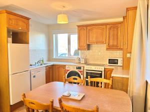 a kitchen with wooden cabinets and a table and a refrigerator at The Seafarers Rest in Cobh