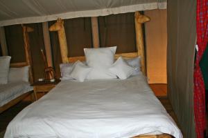 a bed with white sheets and pillows in a tent at Roika Tarangire Tented Lodge in Kwa Kuchinia +18 photos