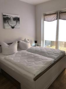 a white bed in a bedroom with a window at Ferienhaus zur Eiche am Dorfanger in Waldow +9 photos