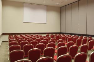 an empty lecture room with red chairs and a screen at Grand Palladium Imbassaí Resort & Spa - All Inclusive in Imbassai