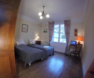 1 dormitorio con 2 camas, escritorio y ventana en Les Glycines, en Vic-sur-Cère