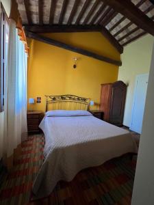 a bedroom with a bed and a yellow wall at La Stazione in Cordovado