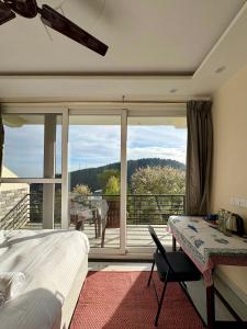 a bedroom with a bed and a view of a balcony at Soma House Dharamkot in McLeod Ganj