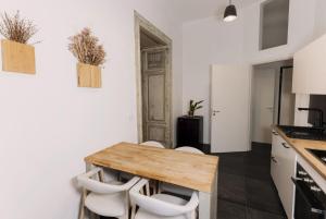 a kitchen with a wooden table and white chairs at Larco Trieste studio living 3 in Trieste +17 photos