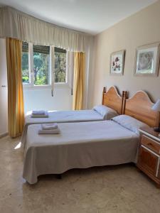 a bedroom with two beds and two windows at Apartamentos Coronado in Marbella +42 photos