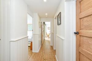 a hallway with white walls and a wooden door at Beach View - East Wittering in Chichester