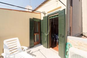 ヴェネツィアにあるVenice Altanina Apartmentの緑のドアが付いた建物の外に座る白い椅子