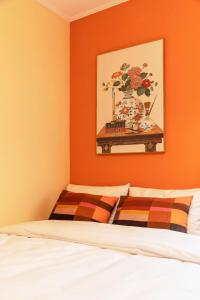 a bedroom with an orange accent wall and a bed at 101STAYㅣFamily-FriendlyㅣStn 1minㅣ2BR 3BedsㅣPrivate Houseㅣ6 GuestsㅣPrivate Yard #DDP #경복궁 #남산 #명동 #홍대 #성수 in Seoul