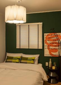 a bedroom with a green wall with a bed and a window at 101STAYㅣFamily-FriendlyㅣStn 1minㅣ2BR 3BedsㅣPrivate Houseㅣ6 GuestsㅣPrivate Yard #DDP #경복궁 #남산 #명동 #홍대 #성수 in Seoul +53 photos