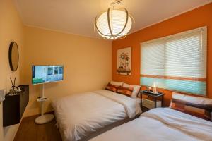 a bedroom with two beds and a flat screen tv at 101STAYㅣFamily-FriendlyㅣStn 1minㅣ2BR 3BedsㅣPrivate Houseㅣ6 GuestsㅣPrivate Yard #DDP #경복궁 #남산 #명동 #홍대 #성수 in Seoul