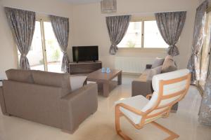 een woonkamer met een bank en stoelen en een tv bij Anthorina Villa 19 in Protaras