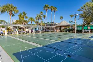 a tennis court with palm trees and people on it at Flagler Suites 1 in New Smyrna Beach