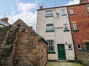 a white building with a green door next to a brick building at Crown Cottage in Belper
