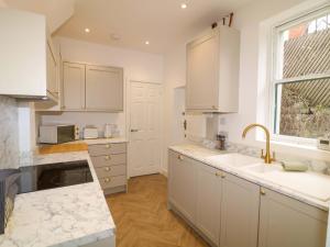 a kitchen with white cabinets and a sink and a window at Crown Cottage in Belper