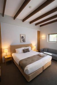 a bedroom with a large bed and a couch at Hahndorf Motel in Hahndorf