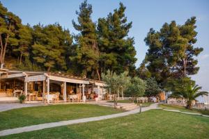 a restaurant with tables and chairs in a park at Elani Bay Resort in Siviri