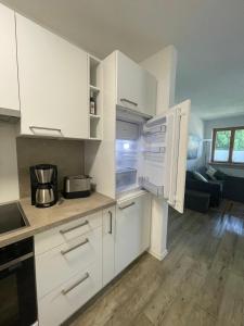 a white kitchen with white cabinets and a living room at Ferienwohnung Bergblick in Marquartstein +34 photos