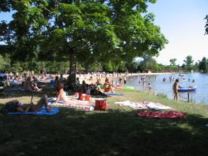 a group of people laying on the grass at a lake at "Côté plage" in Aubeterre-sur-Dronne