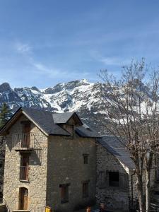 a building with snow covered mountains in the background at Casa Miradell in Hoz de Jaca