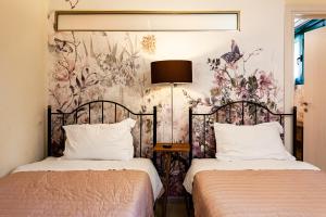 two beds in a bedroom with a floral wallpaper at Dukes Poolside Houses in Paralio Astros