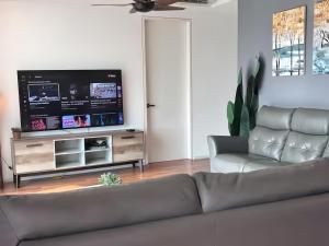 a living room with a couch and a flat screen tv at Sunway Onsen Suite in Tambun