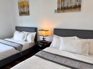 a bedroom with two beds and a lamp on a table at Sunway Onsen Suite in Tambun