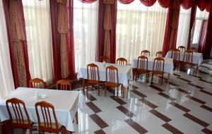 un comedor con mesas blancas y sillas de madera en Weekend, en Mukácheve