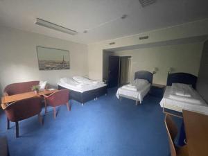 a room with two beds and a table and chairs at Lindum Hotell in Bergjord