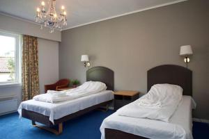 a hotel room with two beds and a chandelier at Lindum Hotell in Bergjord
