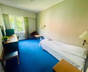 a hotel room with a bed and a desk and window at Lindum Hotell in Bergjord