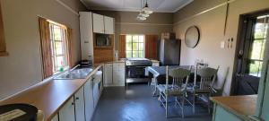 a kitchen with white cabinets and a table and chairs at Ouma Bettie Guesthouse in Piketberg
