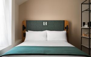 a bed with a green and white headboard in a room at Limehome Versailles Rue du Bailliage in Versailles
