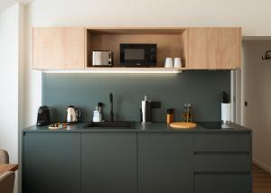 a kitchen with a black counter top with a microwave at Limehome Versailles Rue du Bailliage in Versailles