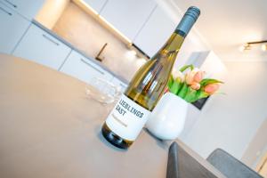 a bottle of wine on a table with a vase of flowers at Villa Seedüwel - App C01 in Ahlbeck