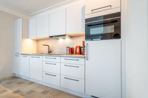 a kitchen with white cabinets and a refrigerator at Villa Seedüwel - App C01 in Ahlbeck +6 photos