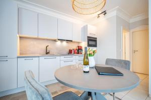 a kitchen with white cabinets and a table with a bottle of wine at Villa Seedüwel - App C01 in Ahlbeck