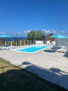 a swimming pool with chairs and umbrellas next to it at Acrita Superior in Mandaradoni