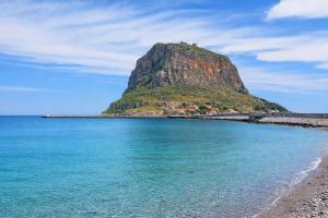 a mountain sitting on top of a body of water at Matroni's House - Seafront Getaway in Monemvasia in Monemvasia