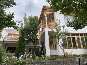 a large white house with windows and flowers at AO Guest House in Nubra