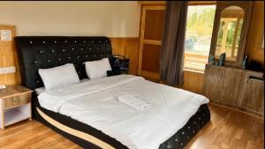 a bedroom with a large bed with a black headboard at AO Guest House in Nubra