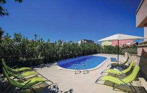 a group of lawn chairs and a pool with an umbrella at Vila Giulietta in Kaštela