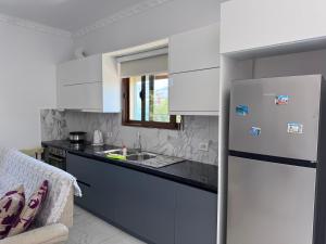 a kitchen with white cabinets and a refrigerator at Handmade Stone Villa in Ksamil